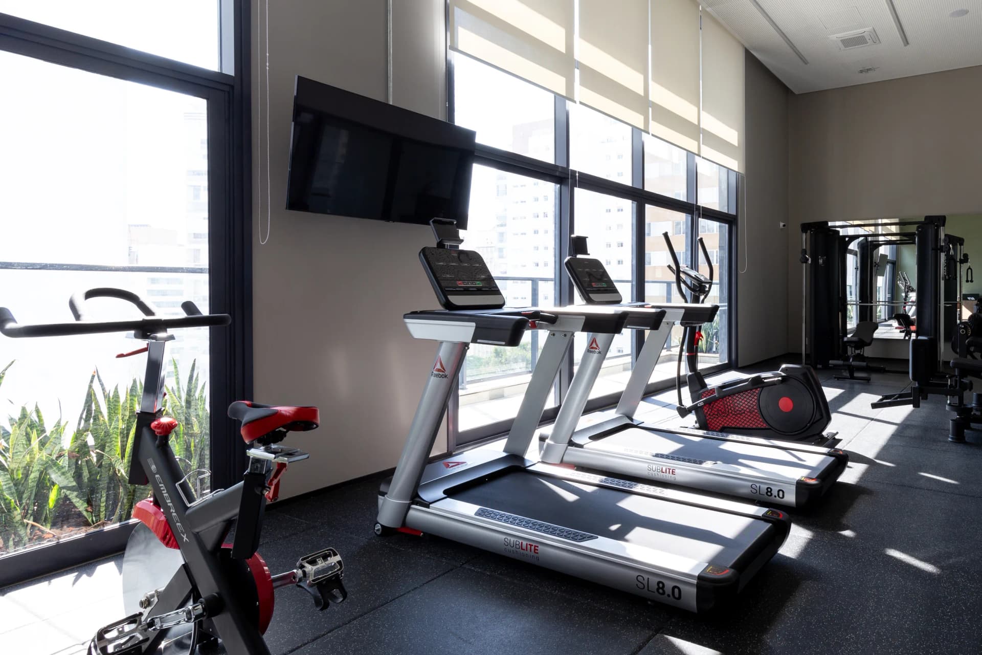 Academia com equipamentos completos em um ambiente com vista privilegiada.
